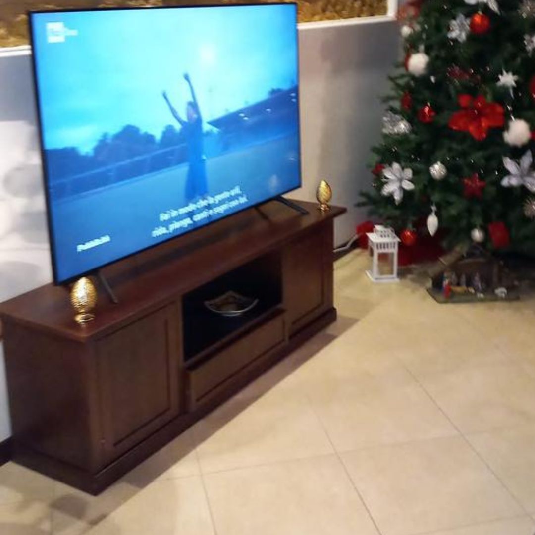 Mobiletto porta TV in legno noce arte povera, posizionato in un soggiorno moderno.